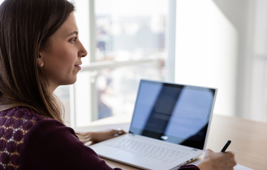 A Suffolk student sits at her laptop on the sixteenth floor of Miller Hall.