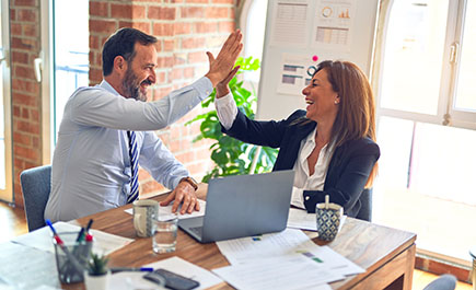 A man and woman smile as they high-five each other